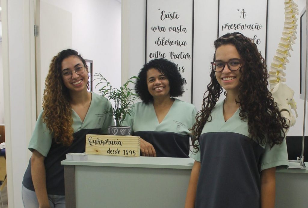 Equipe da Martim Quiropraxia, sorrindo para a câmera, na recepção de nosso consultório. Da esquerda para a direita, Letícia Emídio, Dra. Marcia Martim e Elisa Ferreira.